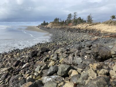 a rocky beach with a house in the distance (MyCoast AI)