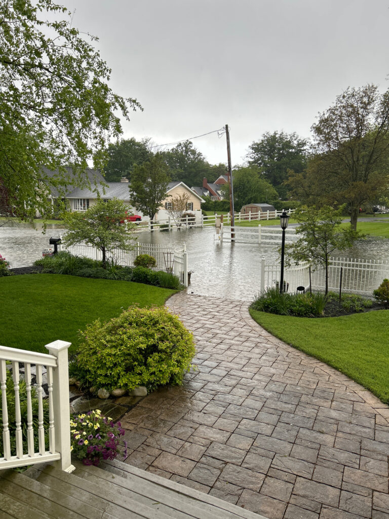 a brick walkway with a white fence and a body of water (MyCoast AI)