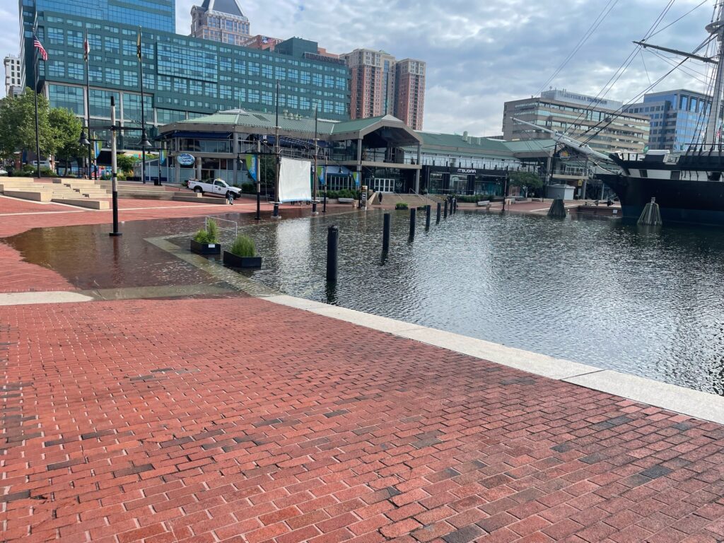 a brick walkway next to a body of water with buildings in the background (MyCoast AI)