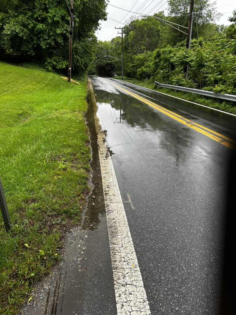 a wet road with grass on the side (MyCoast AI)