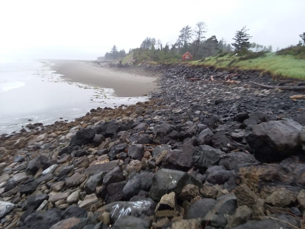 a rocky beach with a house in the background (MyCoast AI)