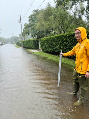 a man in a raincoat holding a white pole (MyCoast AI)