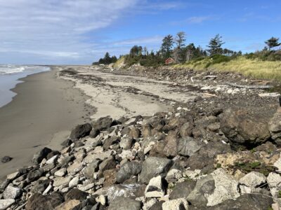 a rocky beach with a house in the background (MyCoast AI)