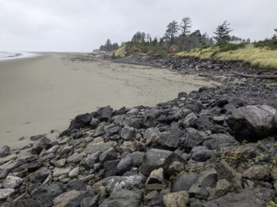 a rocky beach with a house in the background (MyCoast AI)