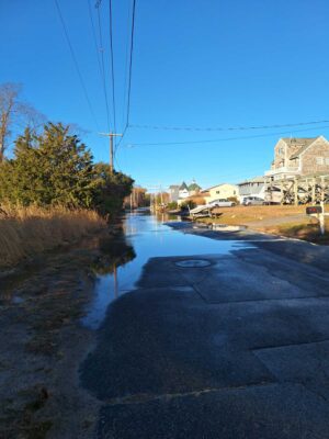a road with a puddle on the side and buildings on the side (MyCoast AI)