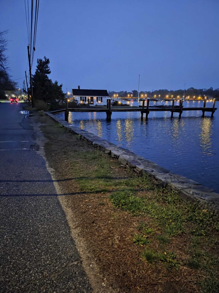a path next to a body of water with a dock and buildings in the background (MyCoast AI)