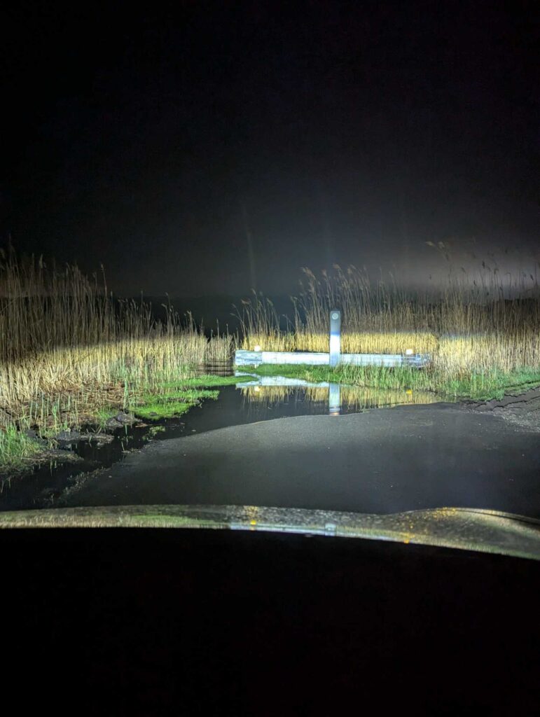 a pond with grass and a fence at night (MyCoast AI)