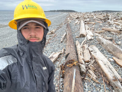a person standing next to a pile of fish on a beach (MyCoast AI)