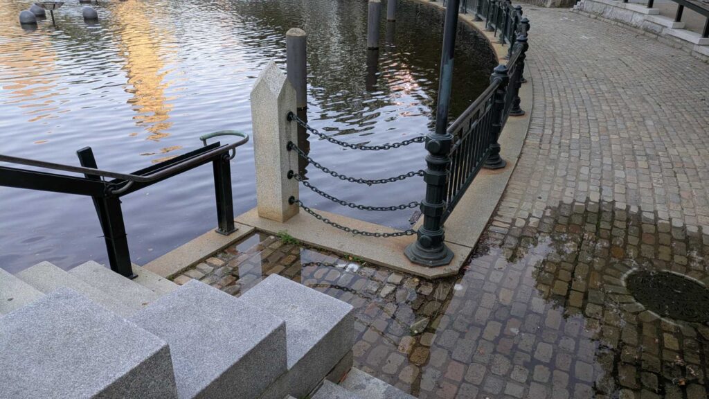 a stone walkway with railings and a body of water (MyCoast AI)