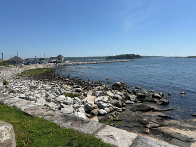 a rocky beach with a pier in the background (MyCoast AI)