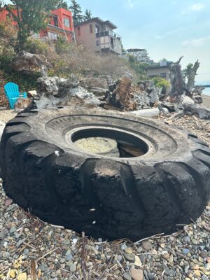 a large black tire on a rocky beach (MyCoast AI)