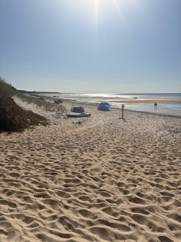 a sandy beach with a tent and a person walking on it (MyCoast AI)