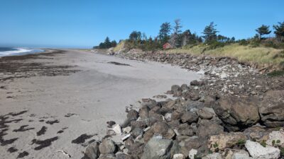 a rocky beach with a house in the distance (MyCoast AI)